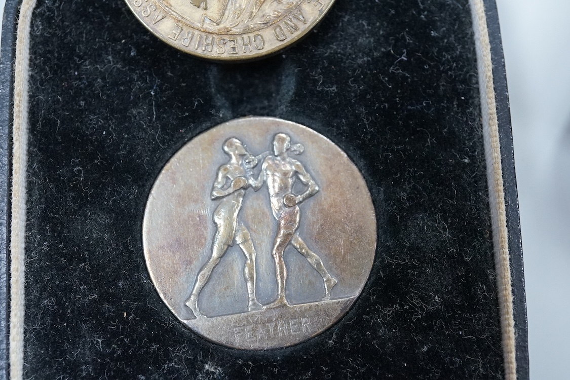 Framed group of eight WWI and WWII medals including a First World War medal pair, the Africa star, the Atlantic star, etc. a hallmarked silver boxing medal and another, both cased, plus a Lancashire and Cheshire Associat